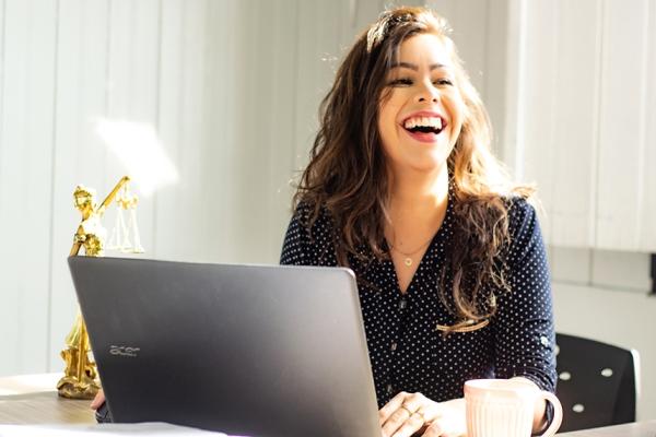Image of woman laughing near a laptop